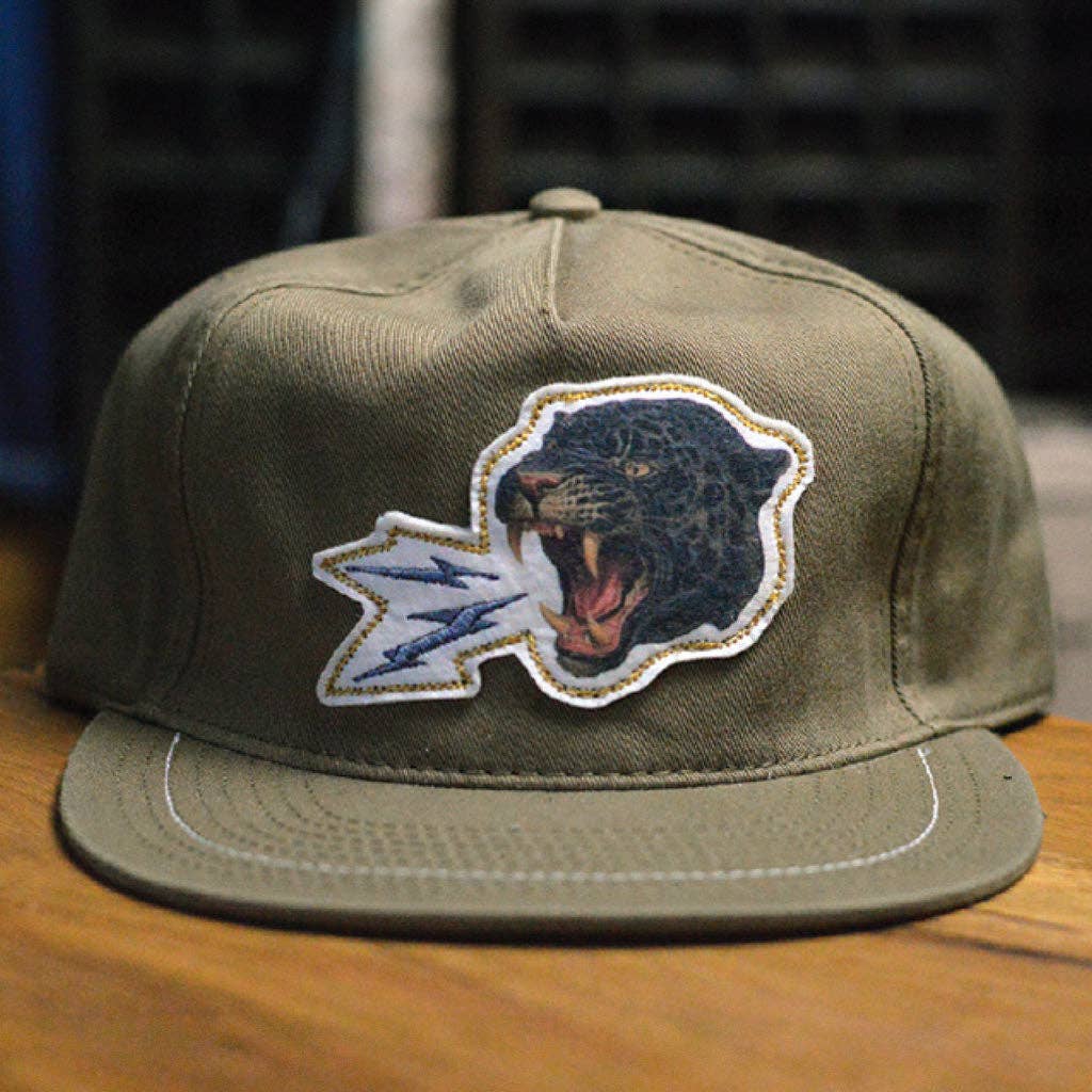 Green cap with a panther logo on a wooden surface