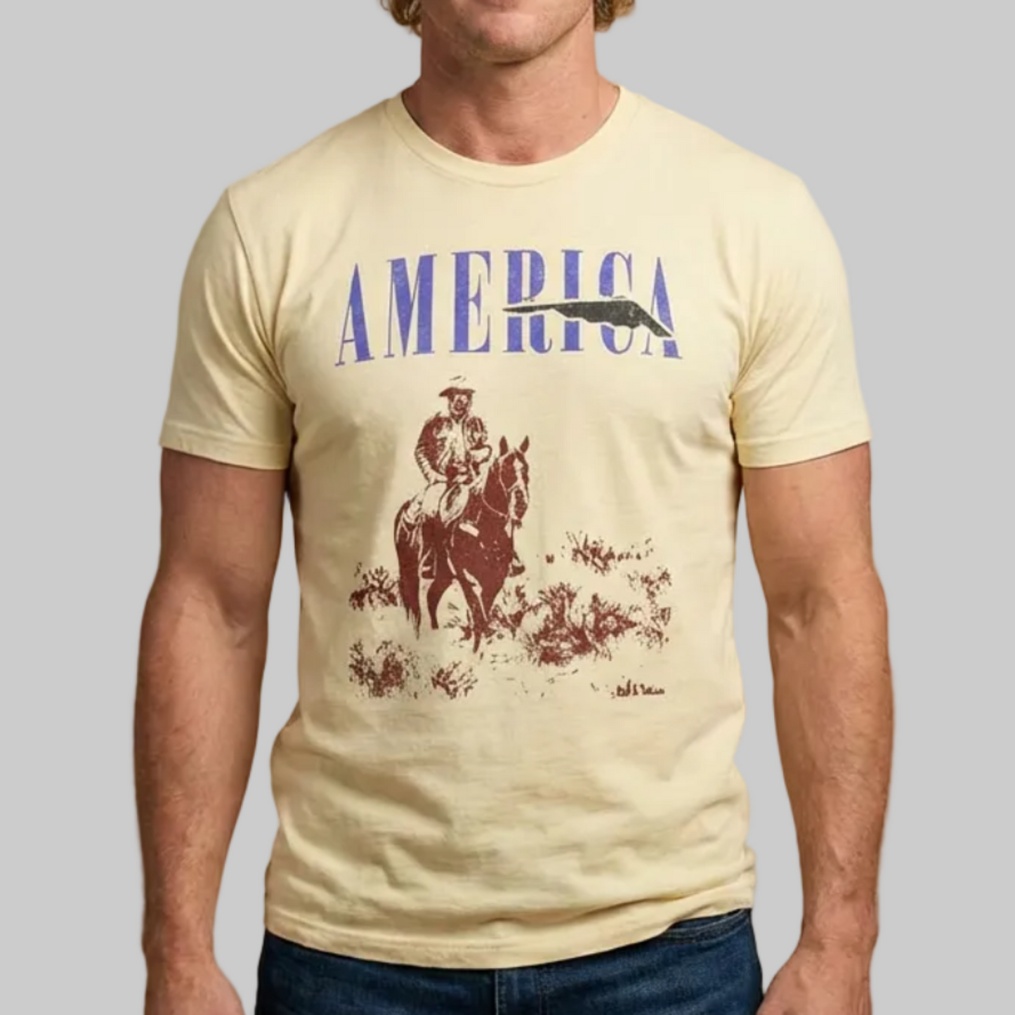 Man wearing a beige t-shirt with 'AMERICA' and a graphic design on a beige background