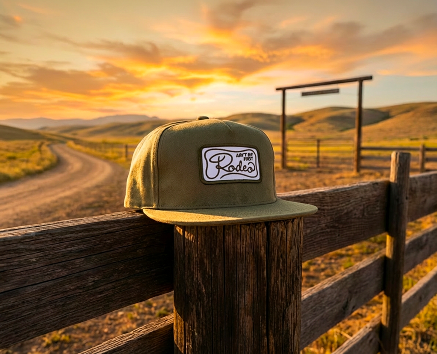 Green cap with a logo on a wooden fence during sunset in a rural landscape