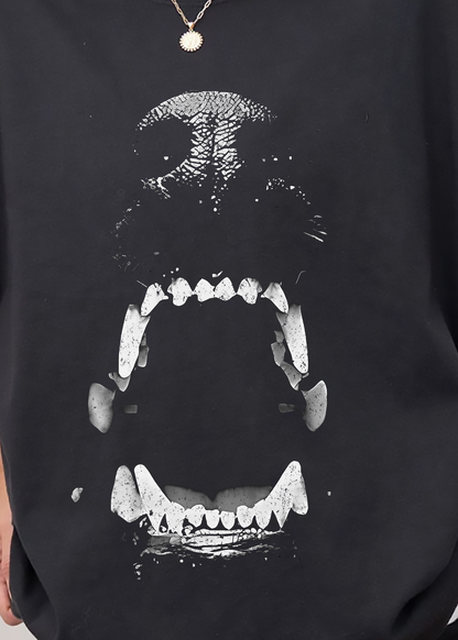 Person wearing a black oversized sweatshirt with a white graphic design on a plain background