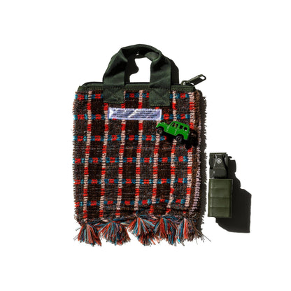 Plaid bag with tassels and a small green toy car on a white background