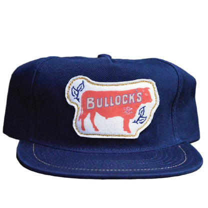 Blue cap with a 'Bullocks' patch on a wooden surface