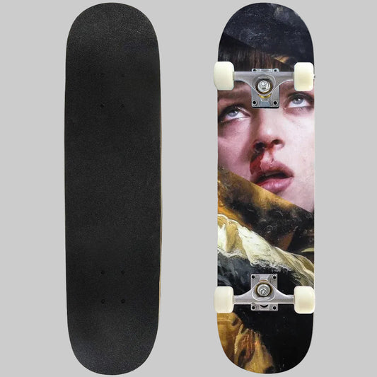 A skateboard shown from two angles on a plain white background: the black grip-slicked underside on the left and the printed top deck on the right, featuring a close-up portrait with dark hair, a black hat, and warm brown/gold tones.
