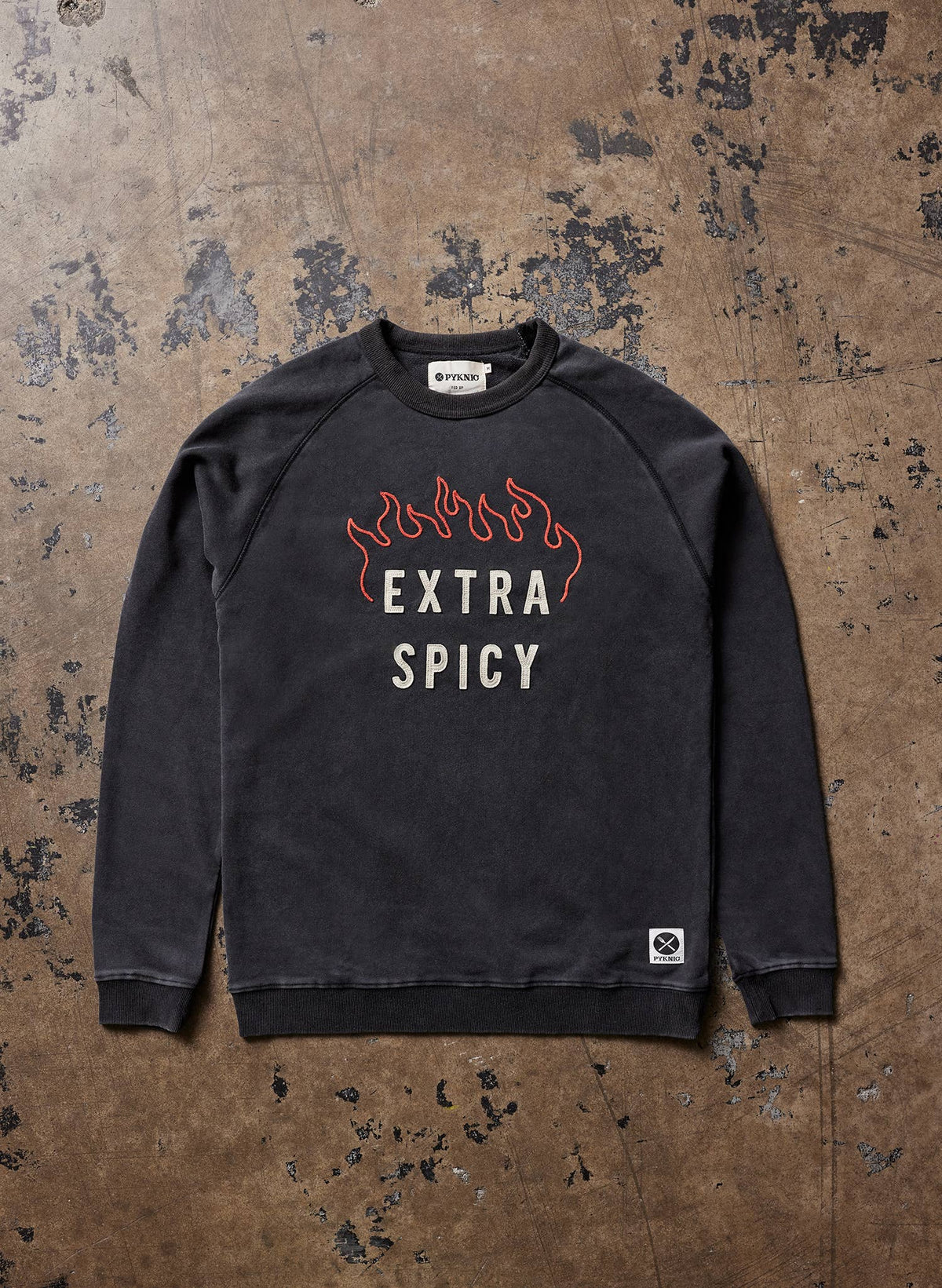 Black sweatshirt with 'Extra Spicy' text on a textured brown background