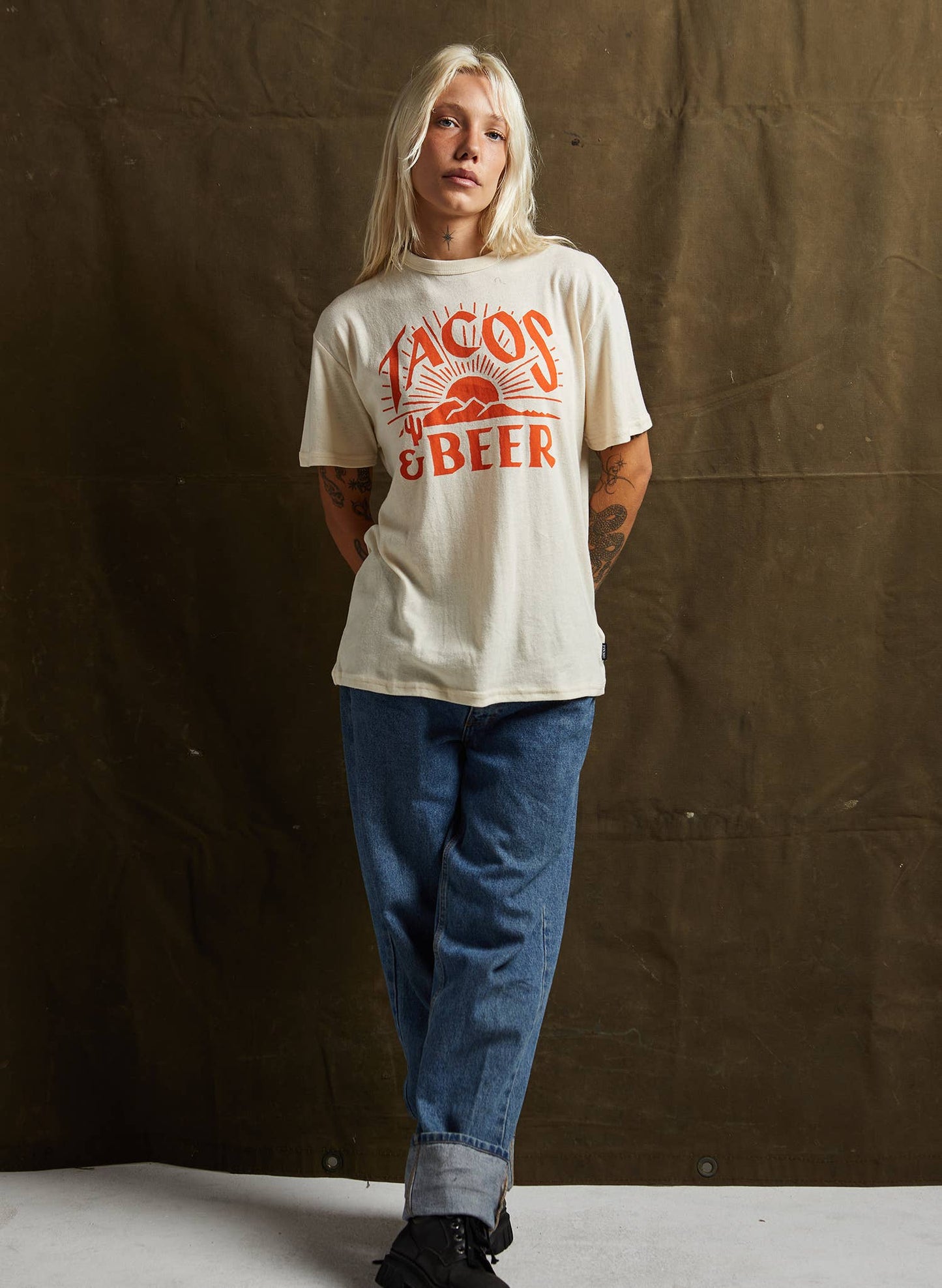 Person wearing a white t-shirt with red text against a brown backdrop