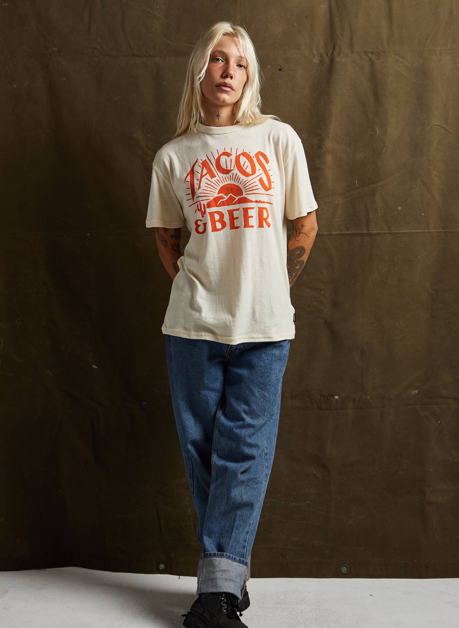 Person wearing a white t-shirt with red text against a brown backdrop