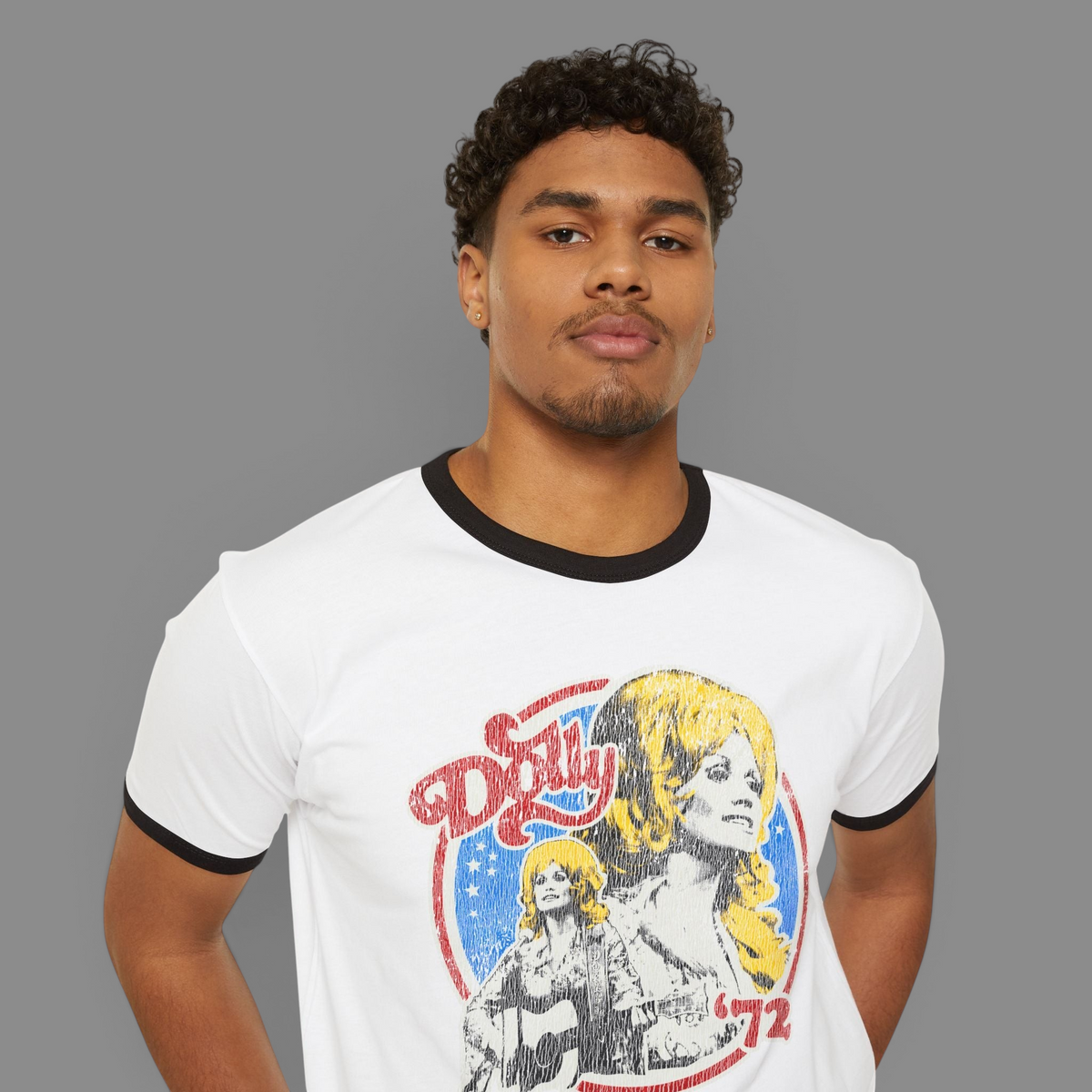 A man wearing a KILLER RETRO cream ringer tee with a navy collar and a vintage Dolly 1972 graphic print.