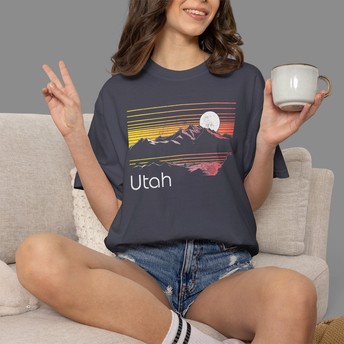 Woman wearing a charcoal KILLER RETRO graphic t-shirt featuring a sunset Utah mountain landscape and moon design.